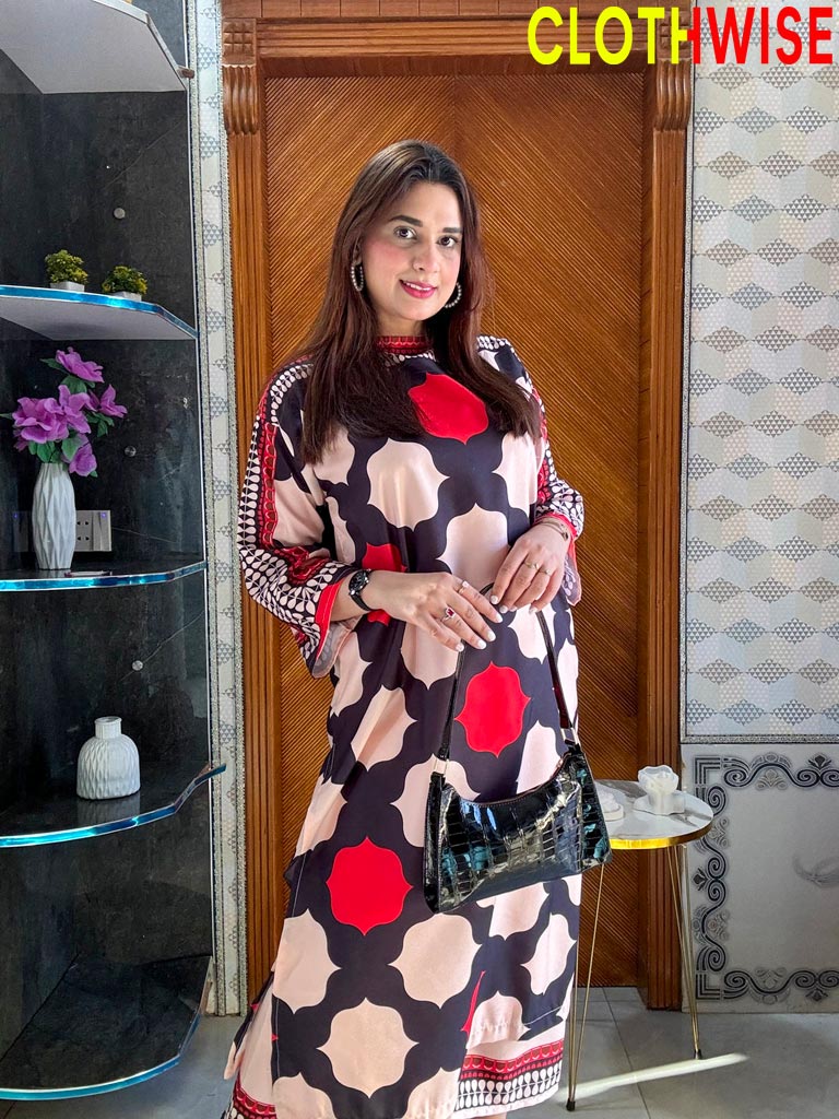 Woman in a patterned dress standing indoors with decor elements in the background