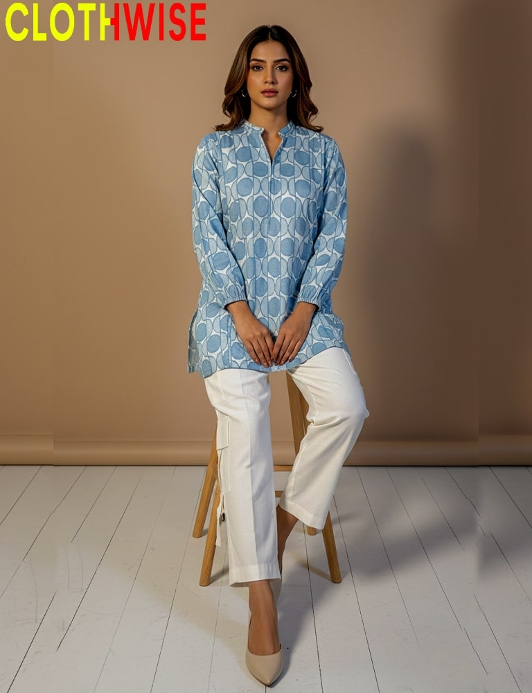 Woman wearing a blue patterned top and white pants sitting on a stool with 'CLOTHWISE' branding.