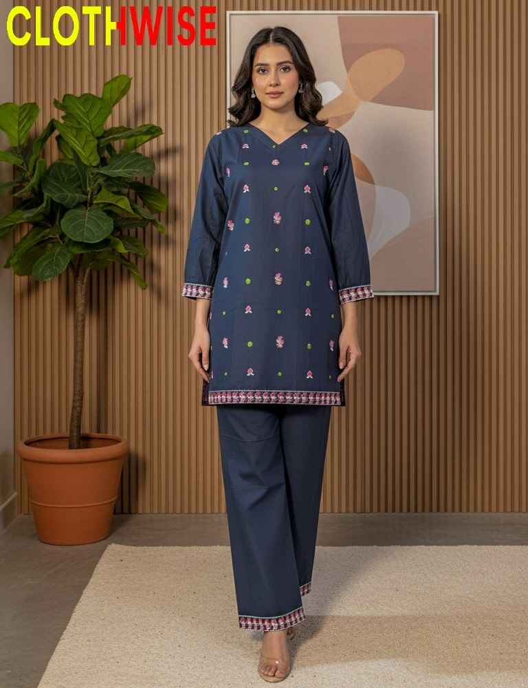 Woman wearing a navy blue outfit with colorful patterns in a room with a plant and abstract painting.