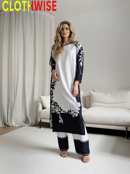 Woman wearing a black and white dress with floral patterns in a modern living room setting.