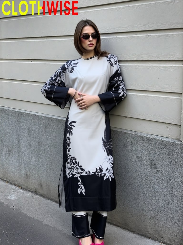 Woman wearing a black and white patterned outfit against a gray wall.