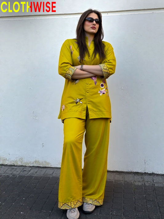 Woman wearing a yellow outfit with floral patterns against a white wall, branded 'CLOTHWISE'.