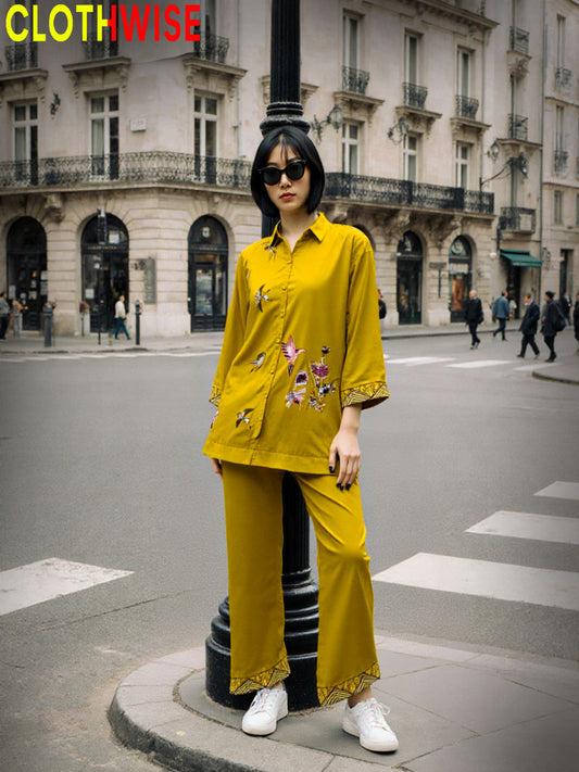 Person wearing a yellow outfit with floral embroidery on a city street, with 'CLOTHWISE' branding.