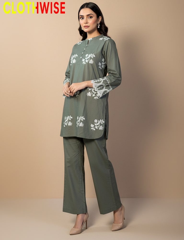 Woman wearing a green outfit with floral embroidery from Clothwise on a beige background