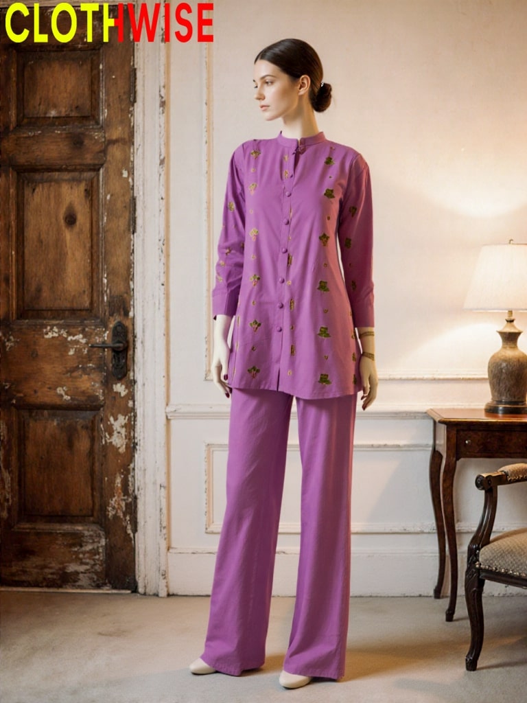 Woman wearing a purple outfit with a pattern in a room with wooden door and lamp.