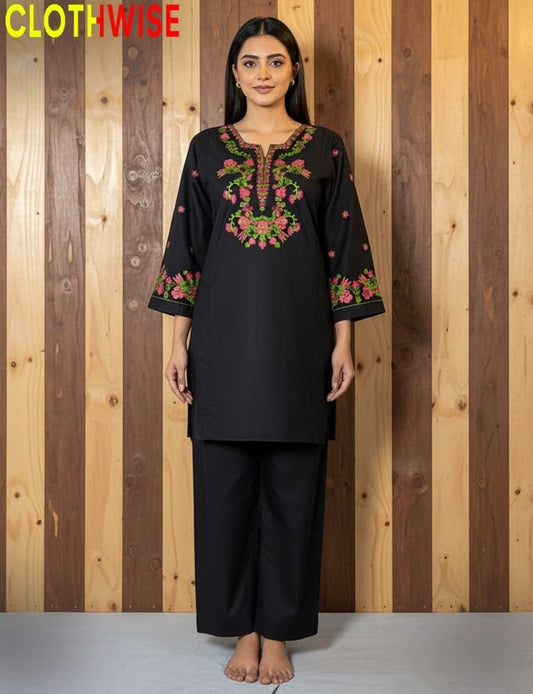 Woman wearing a black embroidered outfit with a wooden striped background, branded 'Clothwise'.