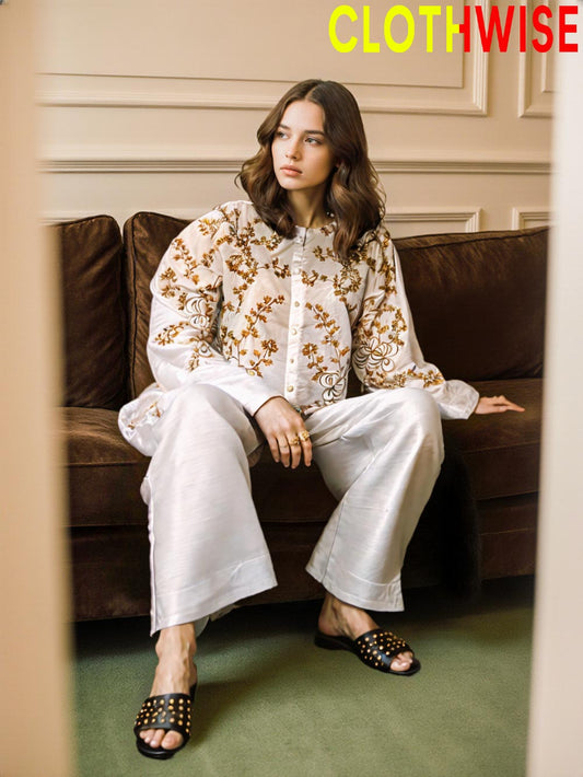 Woman sitting on a brown couch wearing a white outfit with gold patterns, branded 'Clothwise'.