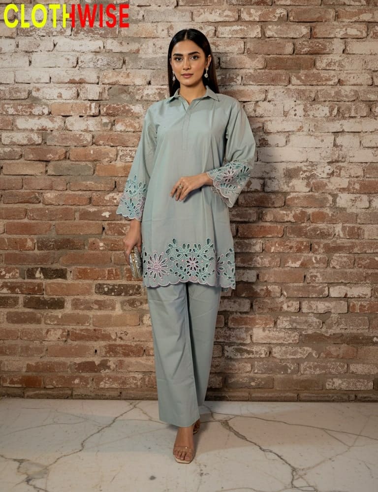 Woman wearing a light gray embroidered outfit against a brick wall with 'CLOTHWISE' branding.