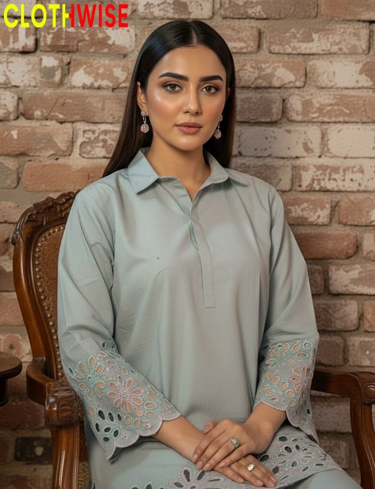 Woman wearing a light blue kurta with lace details sitting against a brick wall.
