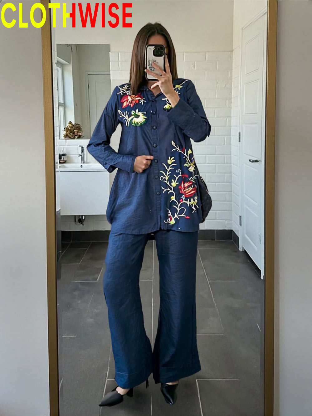 Person wearing a blue outfit with floral embroidery in a bathroom setting, with 'CLOTHWISE' branding.