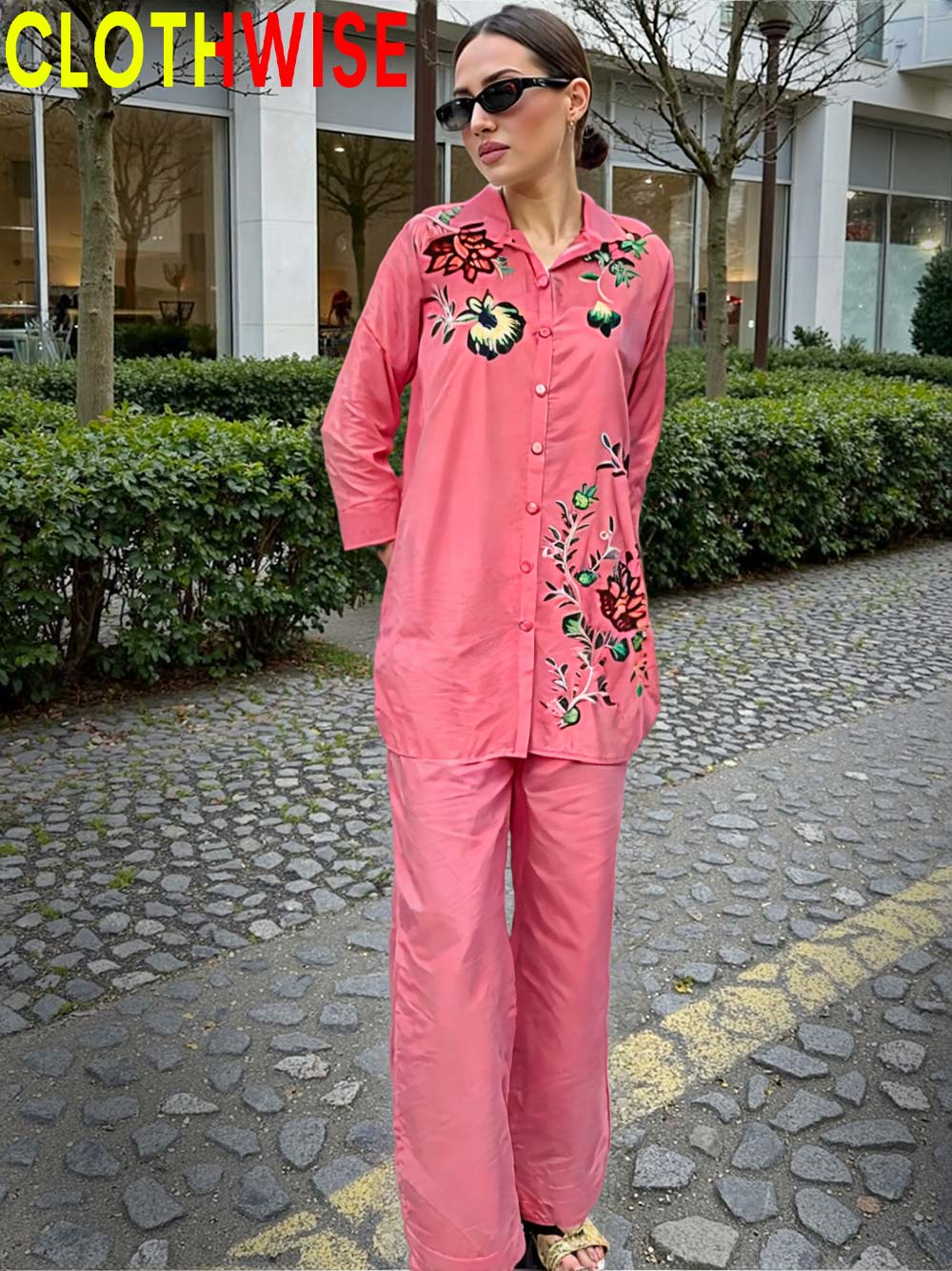 Woman wearing a pink embroidered outfit with 'CLOTHWISE' branding.