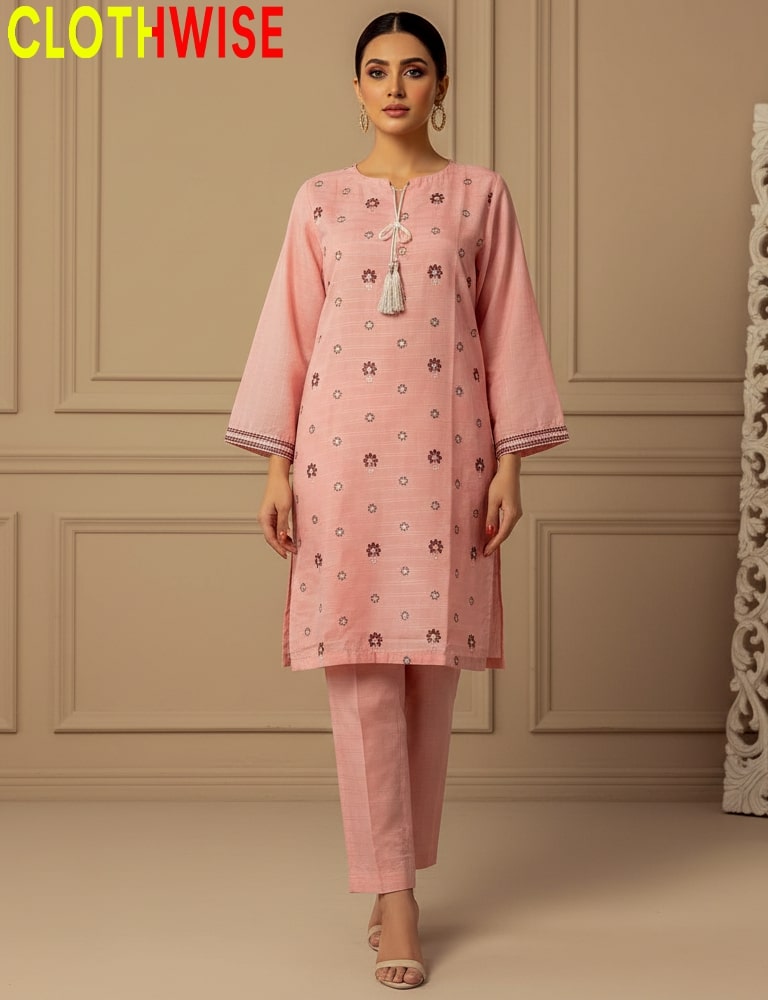 Woman wearing a pink traditional outfit with floral patterns in a room with beige walls.