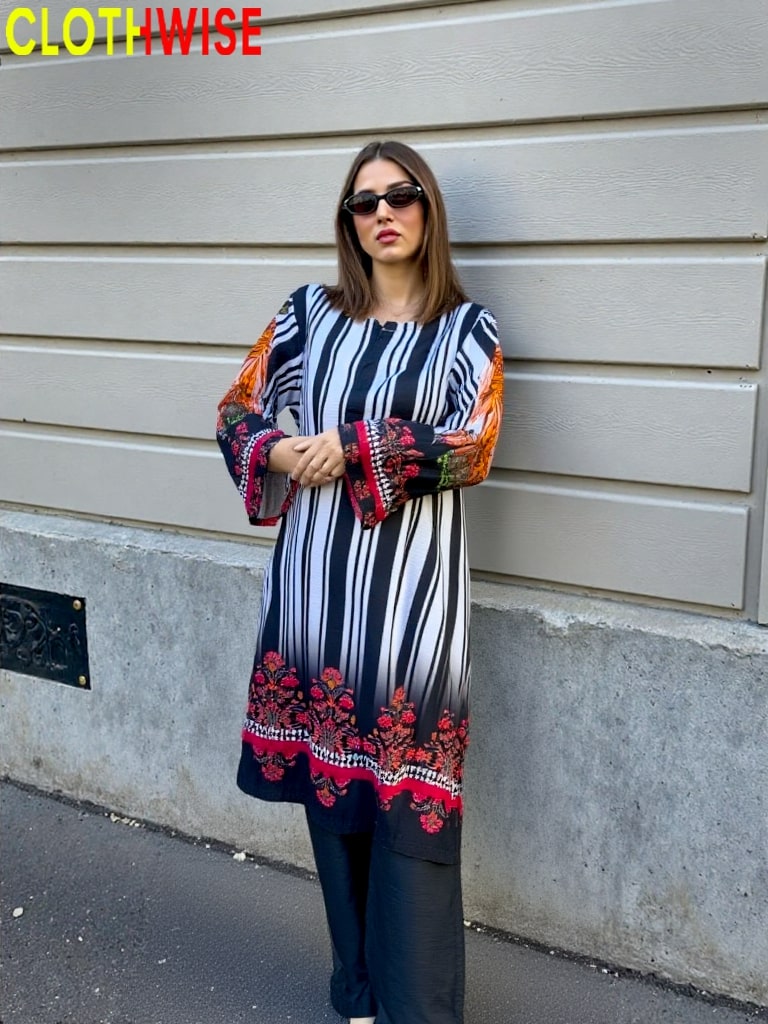 Woman wearing a colorful dress with a striped pattern against a gray wall.
