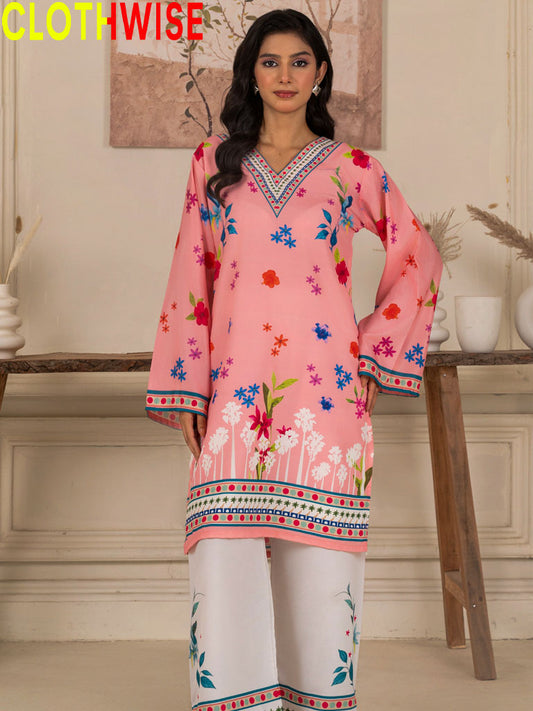 Woman wearing a pink embroidered kurta with white pants in a decorated room.