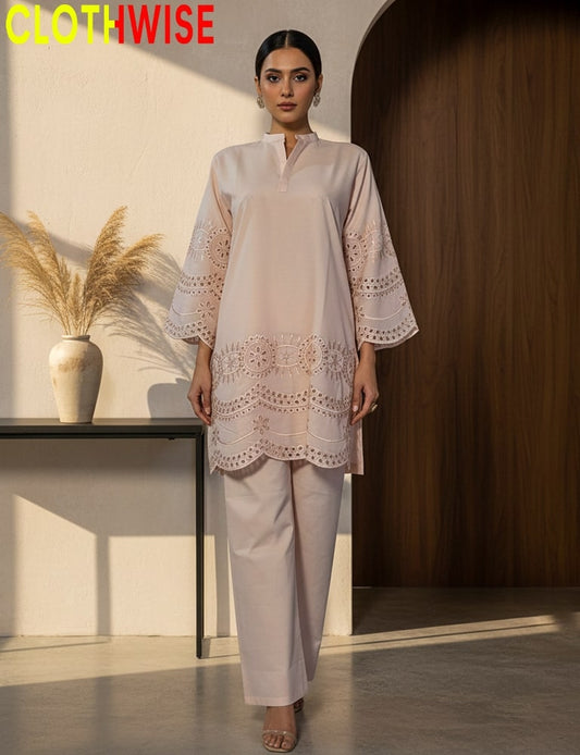 Woman wearing a light pink outfit with lace details in a minimalistic setting.