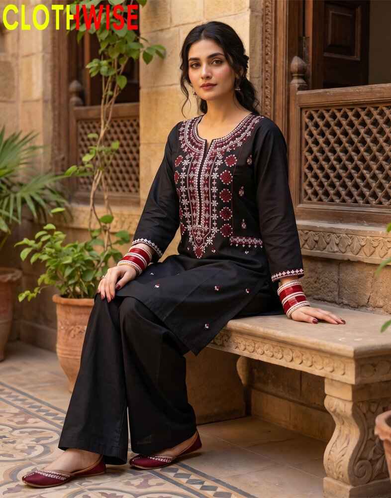 Woman in traditional black outfit with embroidery sitting on a stone bench outdoors.