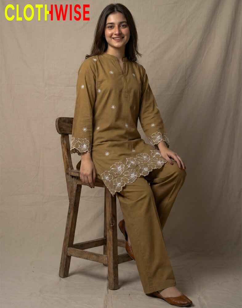 Woman sitting on a wooden stool wearing a brown traditional outfit with lace details, branded 'Clothwise'.