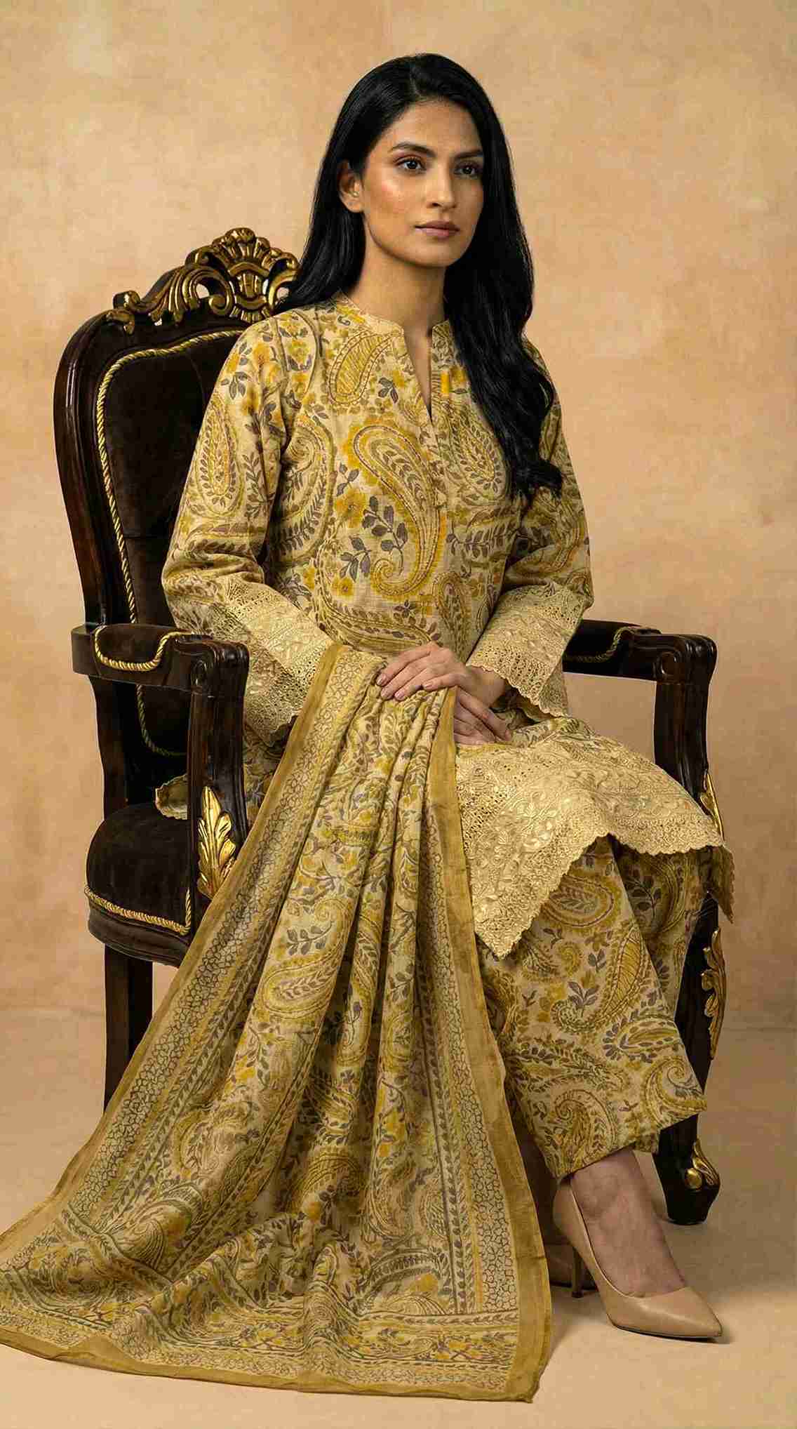 Woman in a yellow and gold traditional outfit sitting on an ornate chair.