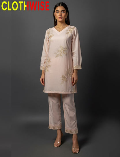 Woman wearing a light pink embroidered outfit with 'CLOTHWISE' branding on a dark background