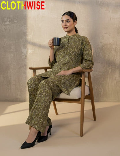 Woman in a green patterned outfit sitting on a chair holding a mug, with 'CLOTHWISE' branding.