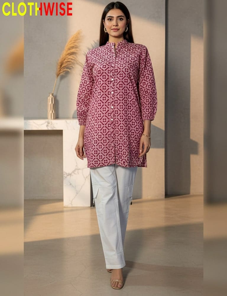 Woman wearing a patterned pink kurta with white pants in an indoor setting.
