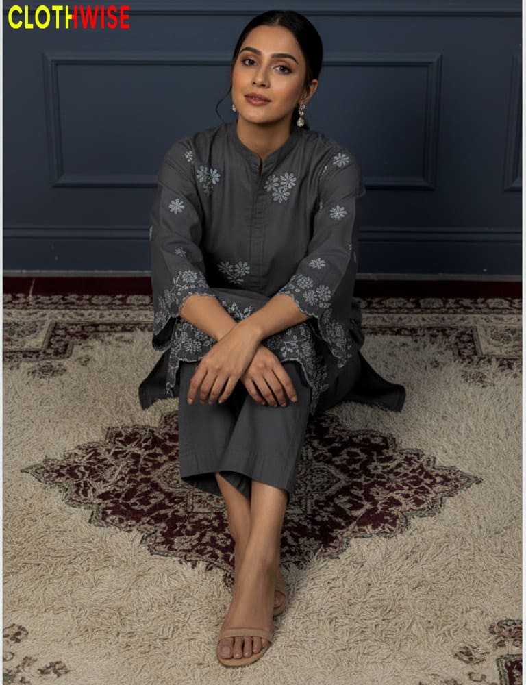 Woman sitting on a patterned rug wearing a gray outfit with floral patterns, with 'CLOTHWISE' branding.