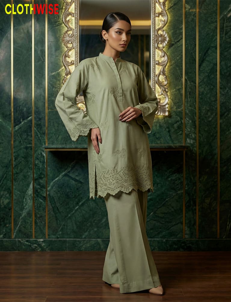 Woman wearing a green traditional outfit with intricate designs in a decorative setting.