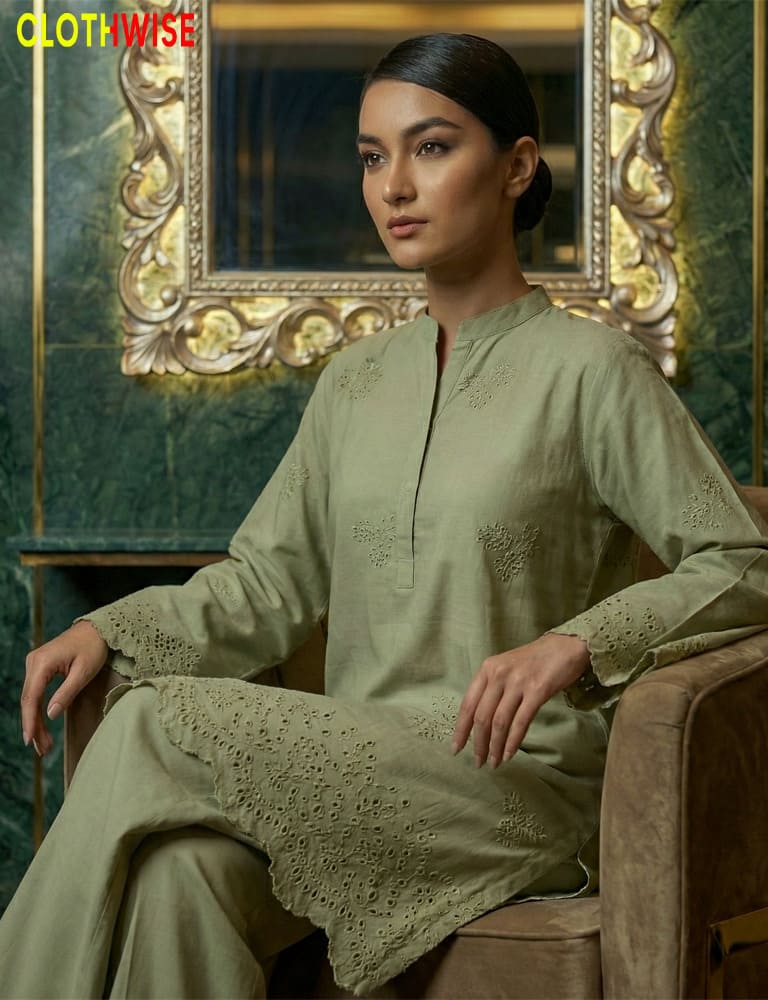 Woman in a green traditional outfit sitting in front of an ornate mirror.