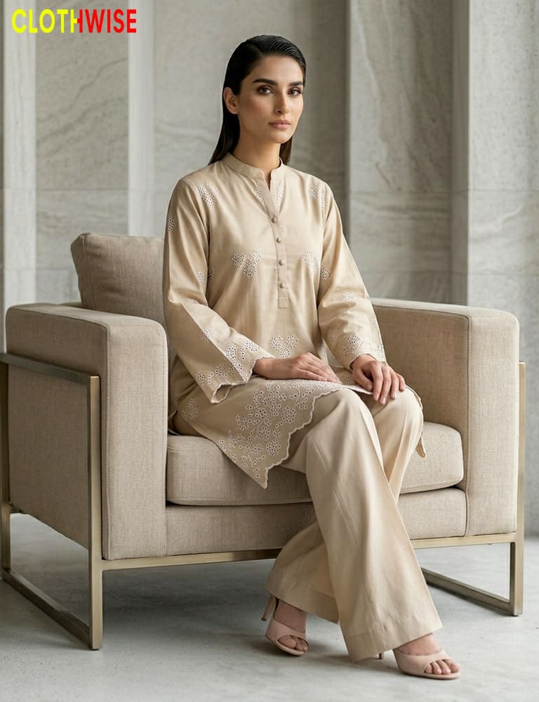 Woman sitting on a beige armchair wearing a beige traditional outfit with 'CLOTHWISE' branding.