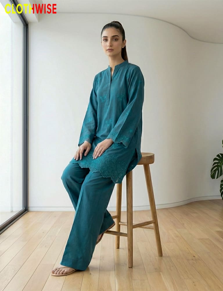 Woman in teal outfit sitting on a wooden stool indoors with 'Clothwise' branding.
