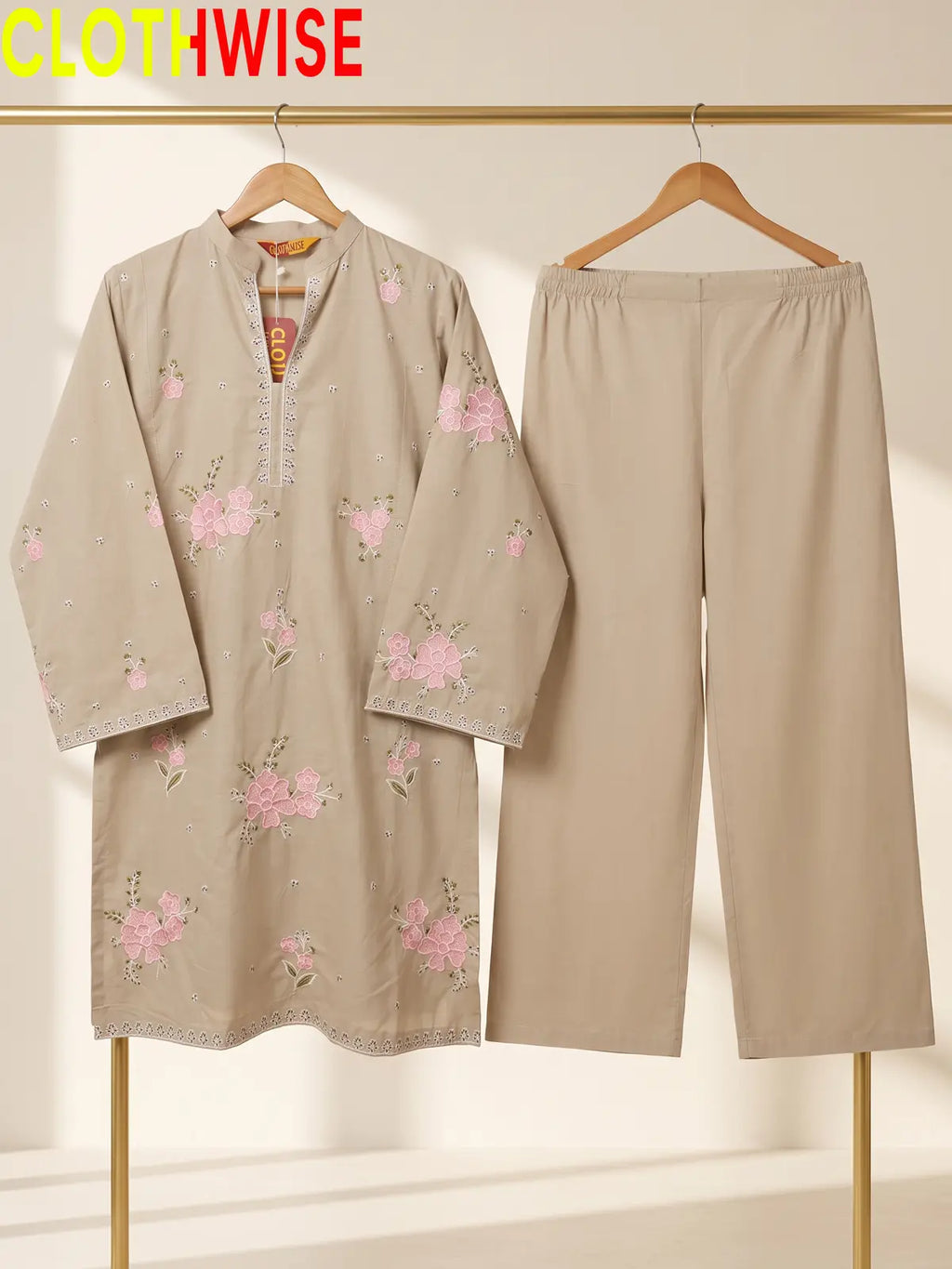 Hanger display of a beige  2-piece stitched outfit featuring a floral embroidered straight shirt and matching wide-leg trousers on a golden metal rack