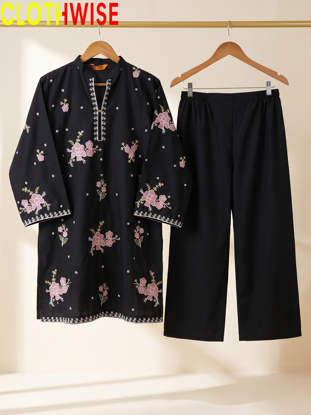 Hanger display of a black 2-piece stitched outfit featuring a floral embroidered straight shirt and matching wide-leg trousers on a golden metal rack
