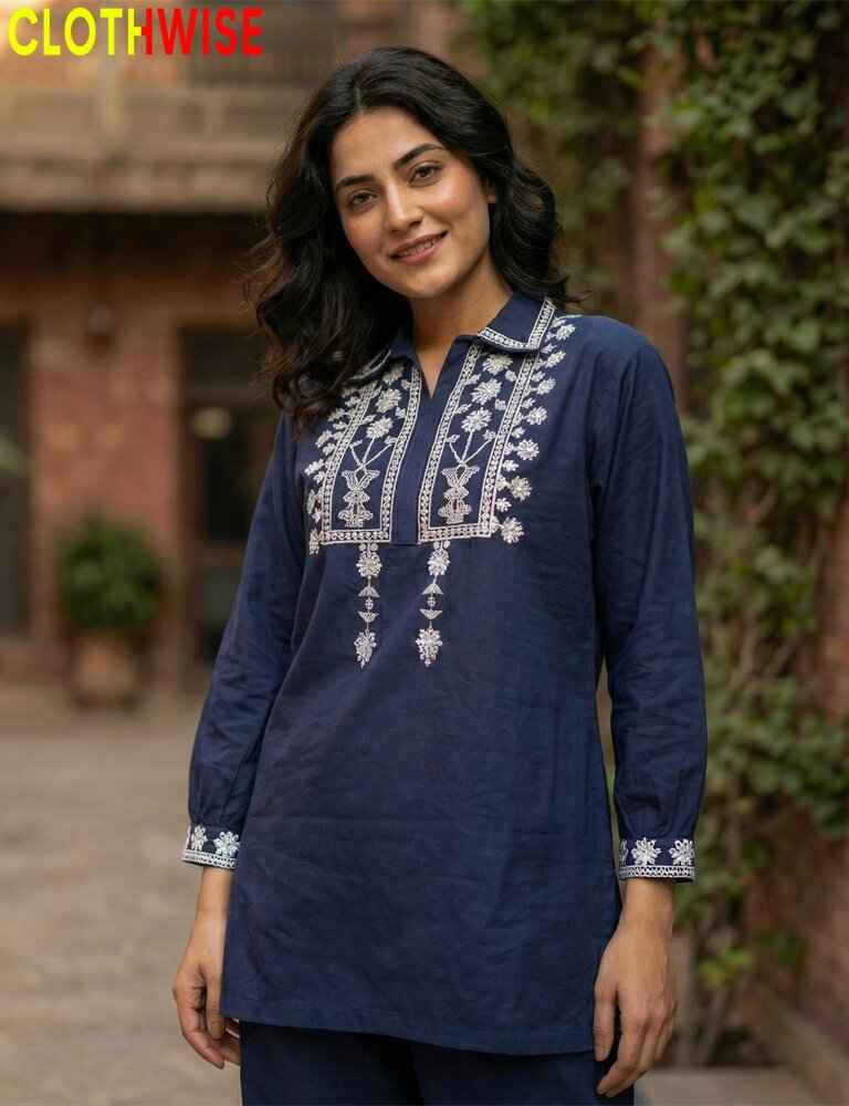 Woman wearing a navy blue embroidered top with white patterns outdoors.