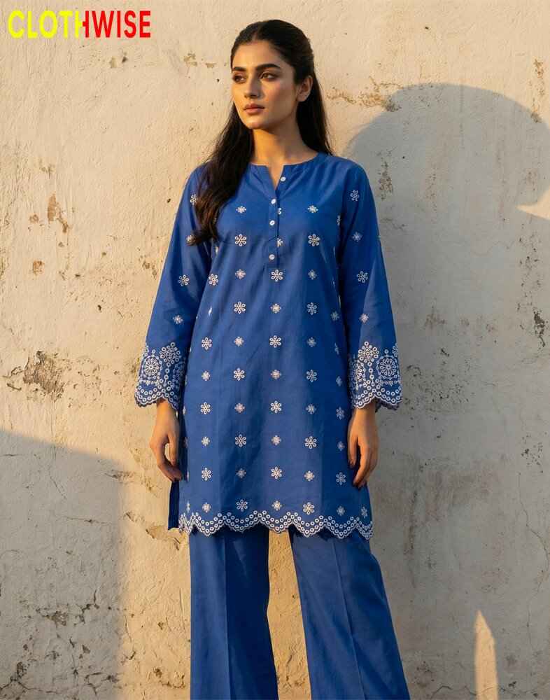 Woman wearing a blue embroidered outfit with a textured wall background