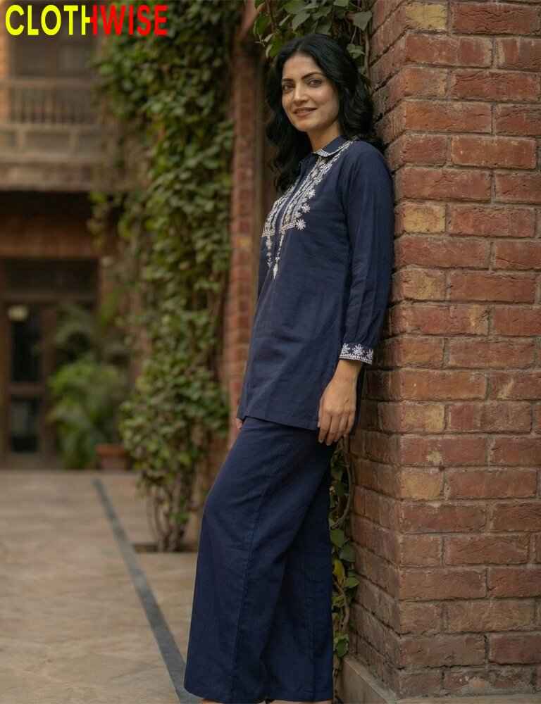Woman wearing a navy blue embroidered top with white patterns outdoors.