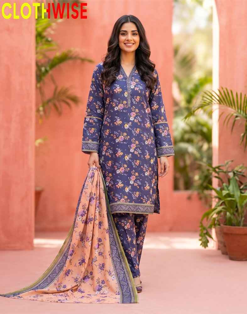 Woman wearing a blue floral dress with a pink dupatta in front of a pink wall with plants.
