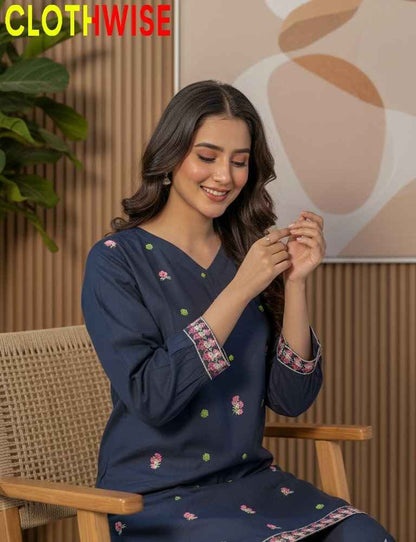 Woman wearing a navy blue embroidered dress sitting on a chair with 'CLOTHWISE' branding.