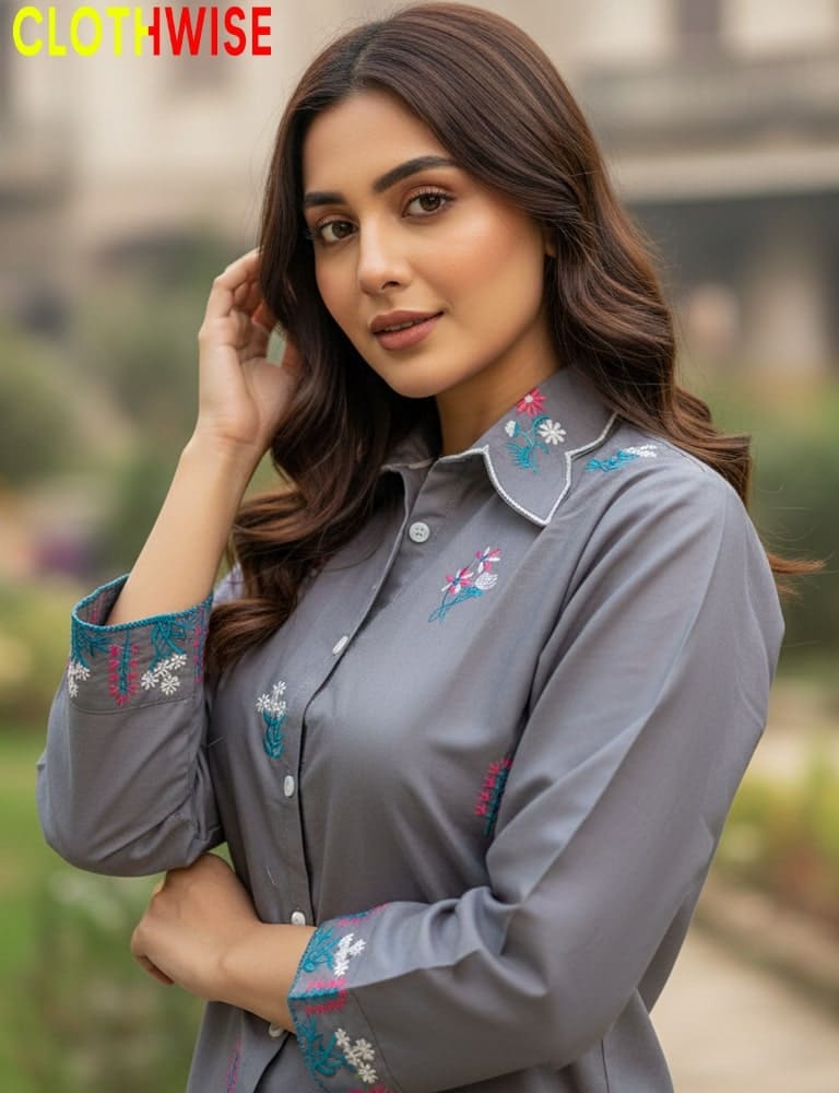 Woman wearing a gray shirt with floral embroidery, standing outdoors.