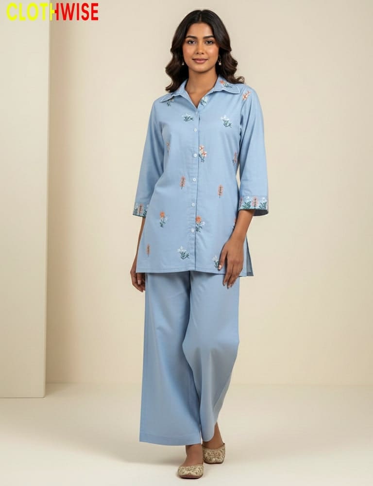 Woman wearing a light blue outfit with floral embroidery, standing against a beige background. Brand 'CLOTHWISE' visible.