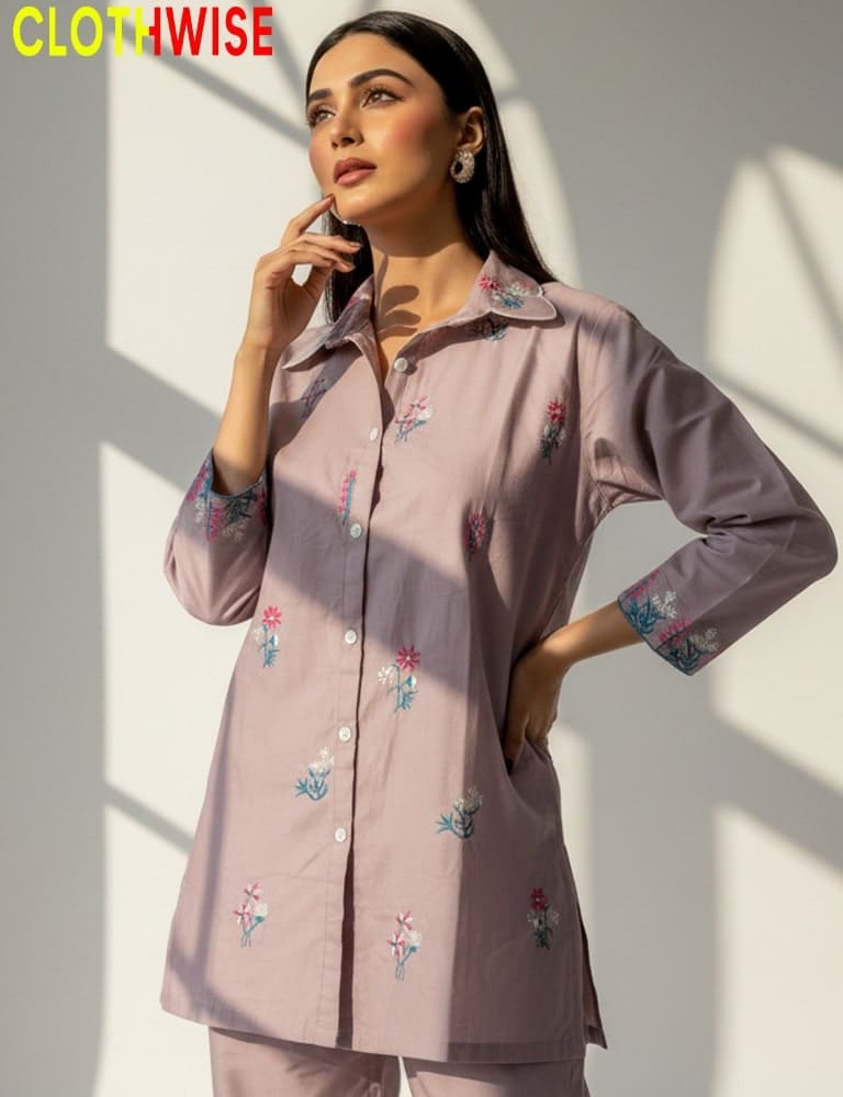 Woman wearing a light pink embroidered shirt with a neutral background, featuring the brand 'CLOTHWISE'.