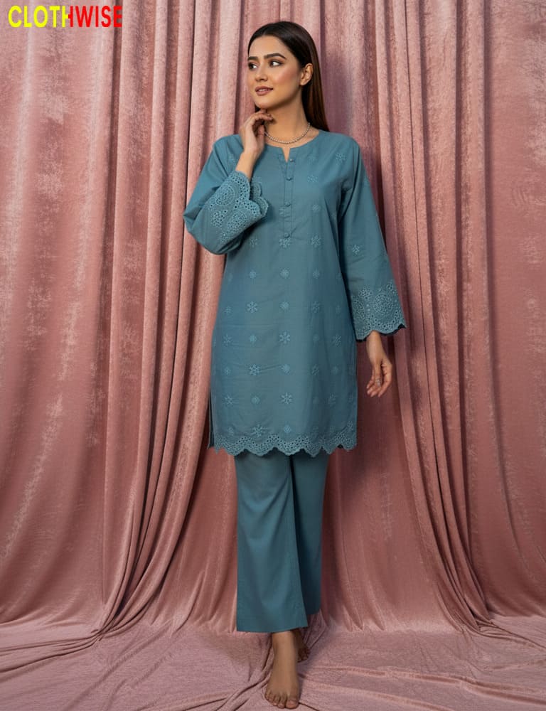 Woman wearing a teal outfit with intricate patterns against a pink curtain background