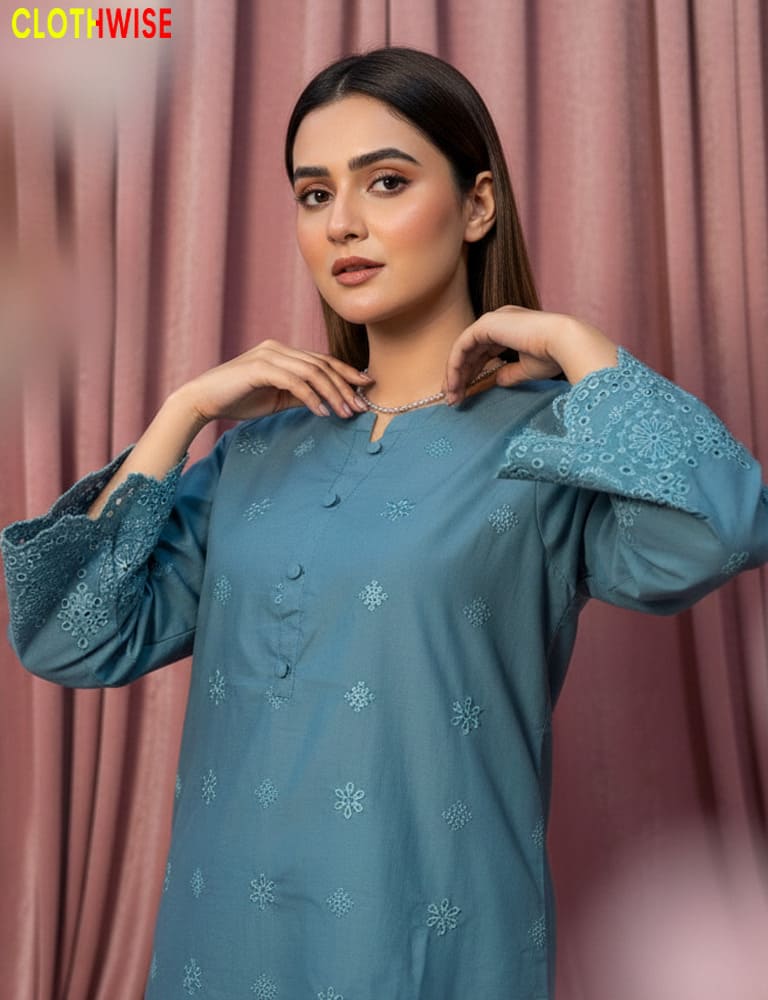 Woman wearing a blue embroidered kurta against a pink curtain background