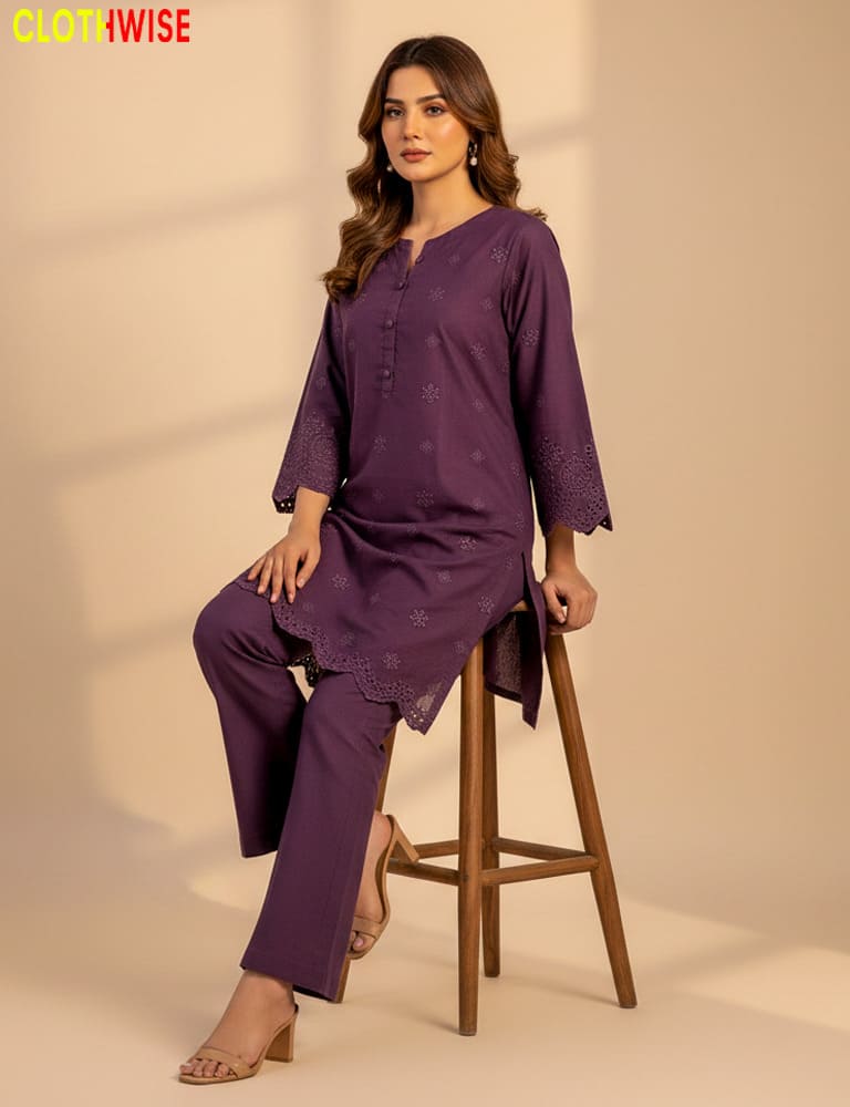 Woman wearing a purple outfit sitting on a wooden stool with a beige background