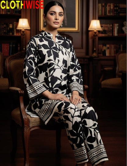 Woman wearing a black and white patterned outfit sitting in a room with bookshelves.
