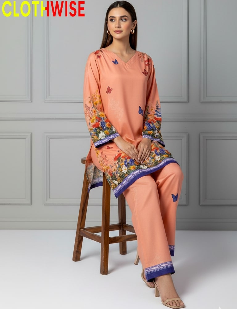 Woman wearing a peach-colored outfit with floral patterns sitting on a wooden stool against a gray paneled wall.