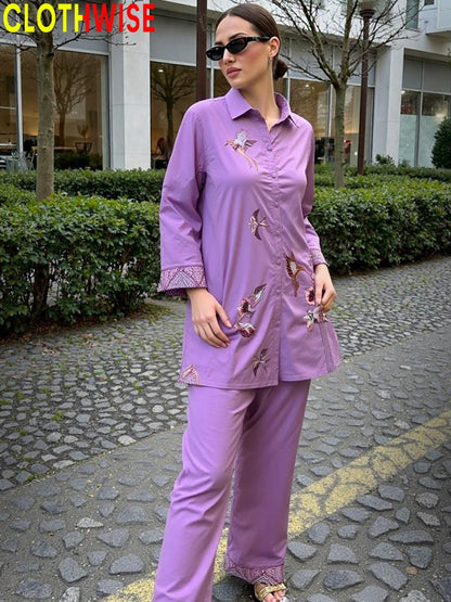 Woman wearing a purple outfit with floral embroidery on a stone path.