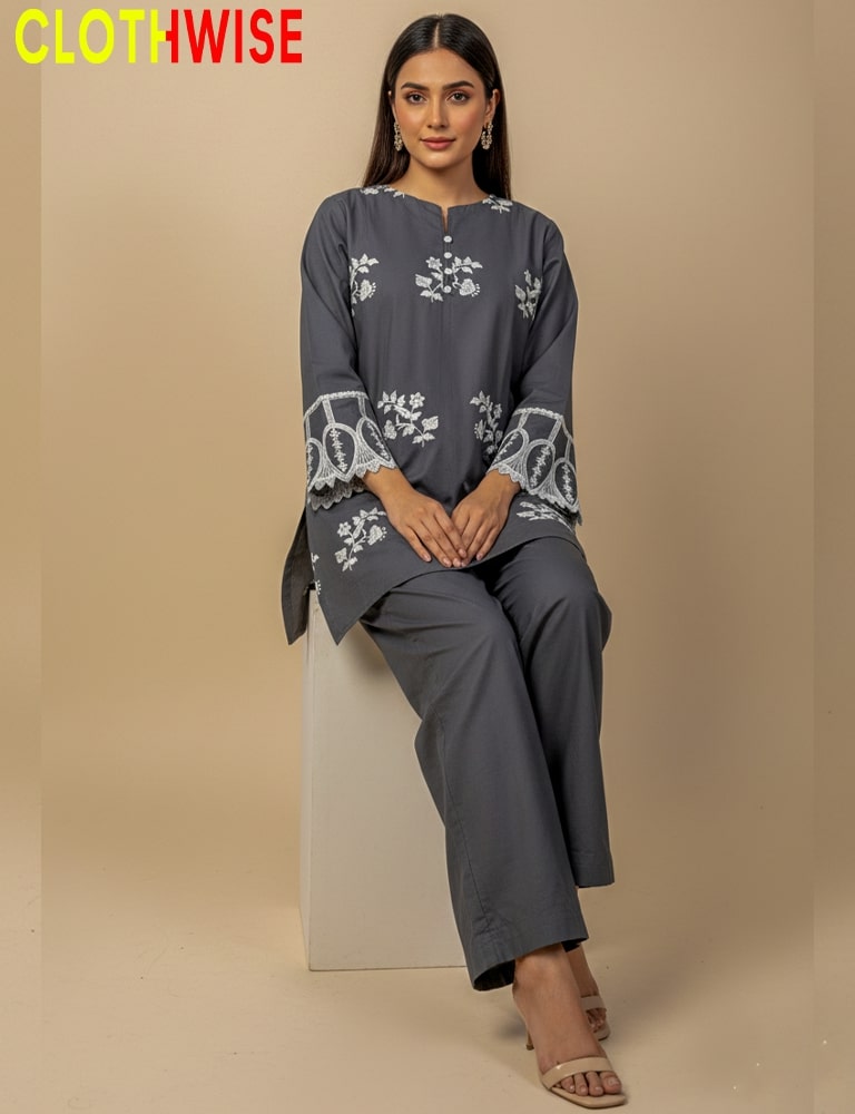 Woman wearing a gray outfit with floral embroidery sitting on a beige block against a beige background, with 'CLOTHWISE' branding.