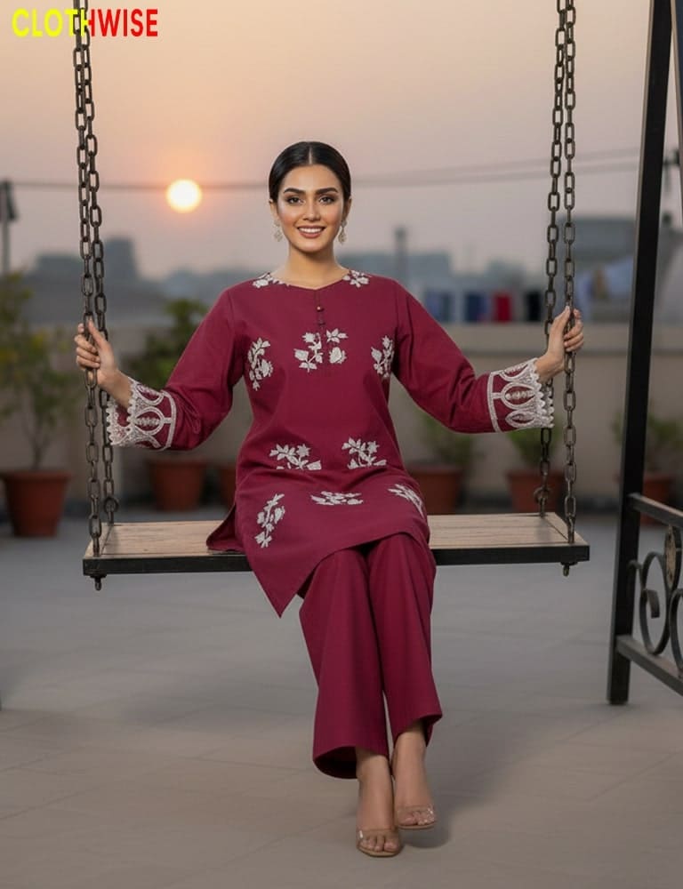 Woman in a maroon traditional outfit with white embroidery sitting on a swing.