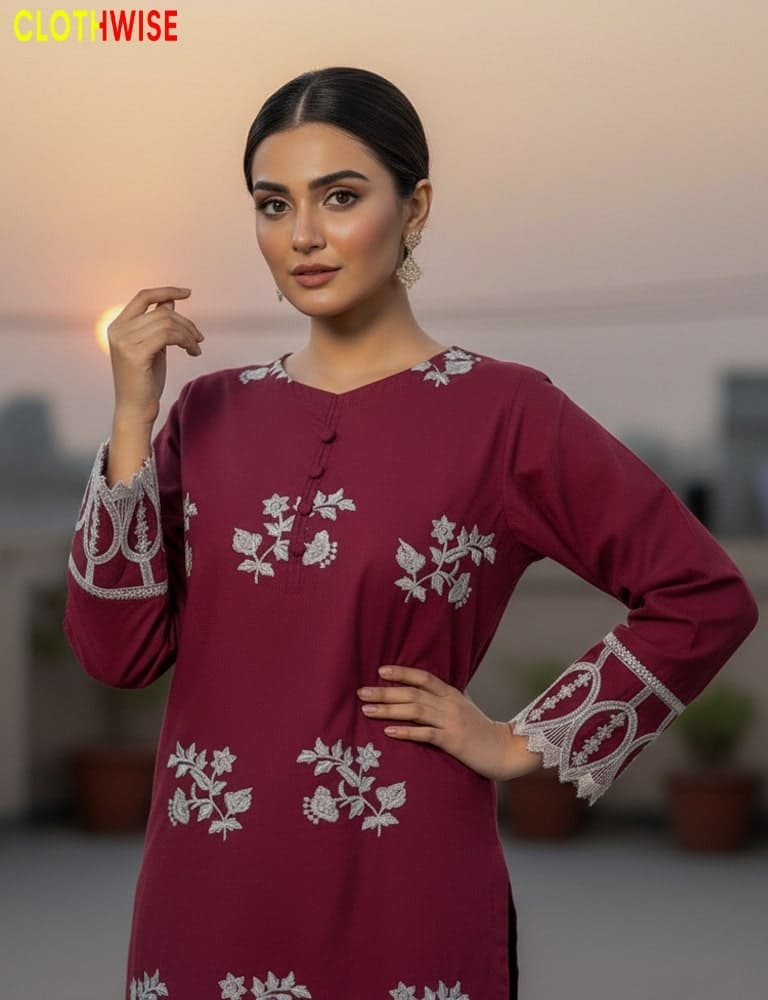 Woman wearing a maroon dress with white floral embroidery, standing indoors.