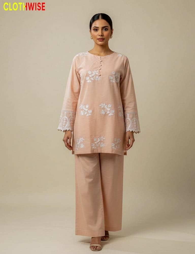 Woman wearing a peach embroidered outfit with a plain background, featuring the brand 'Clothwise'.
